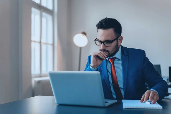Thoughtful businessman in office working on laptop. Thoughtful businessman in office working on laptop.